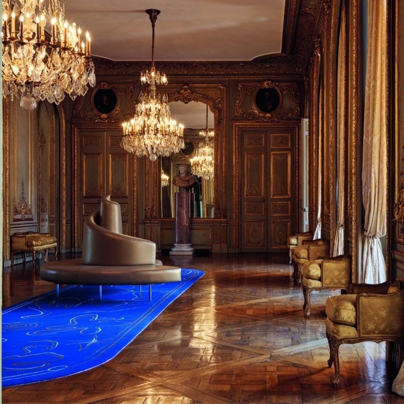  Tatlin in pelle dorata nel grande Salone del Mappamondo, appoggiato su un tappeto disegnato da Daniel Roseberry (Maison Schiaparelli). 