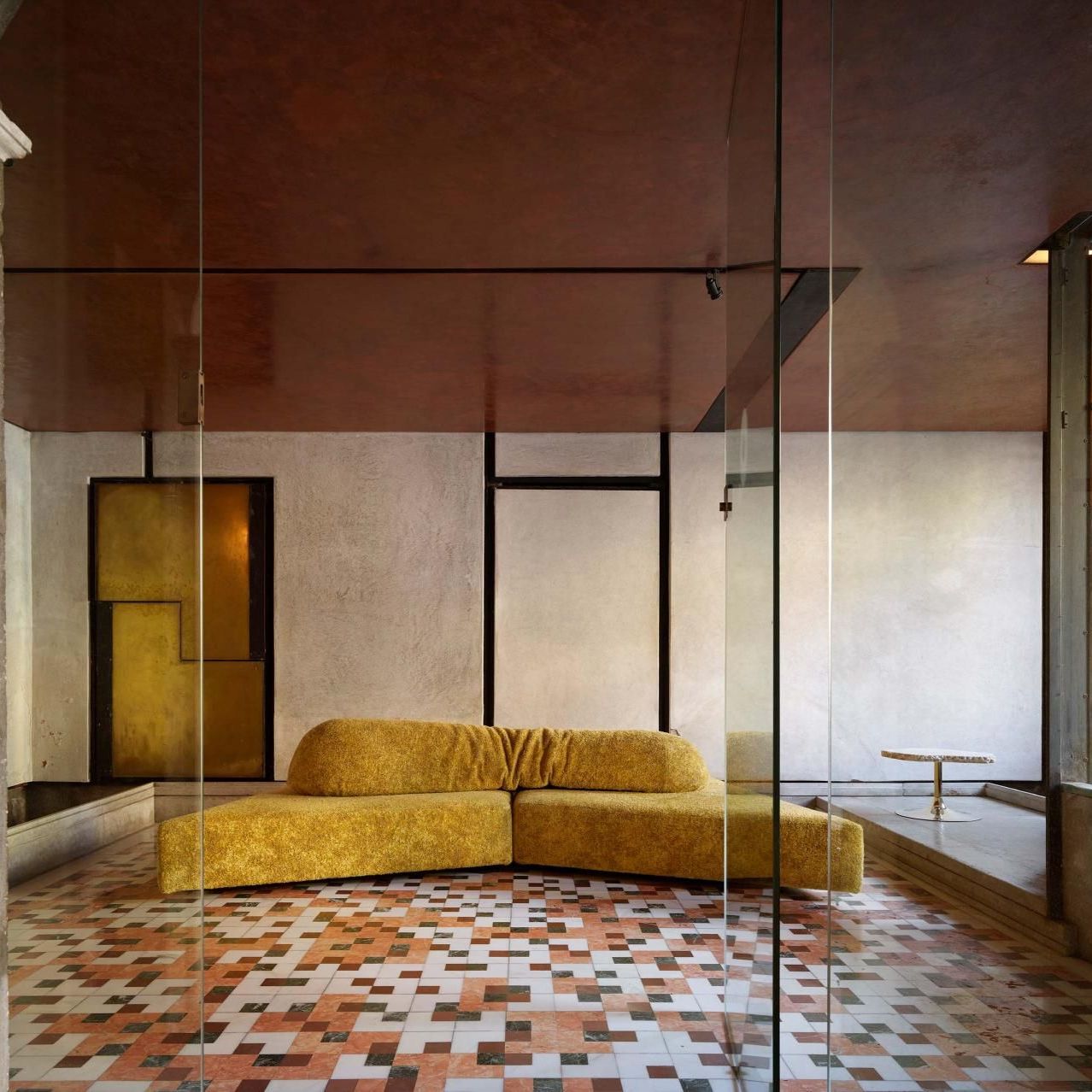  On the Rocks e Cicladi. Il divano rivestito in Every Stone Royal Yellow sul pavimento a scacchiera dell&rsquo;atrio: i marmi policromi risuonano con il soffitto in stucco rosso. 